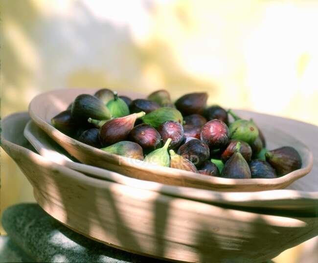 Figues fraîches dans des assiettes en bois à la lumière du soleil — Photo de stock