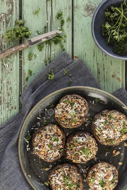 Portobello mushrooms stuffed with parmesan, pine nuts, garlic, breadcrumbs and parsley on green wooden table — Stock Photo