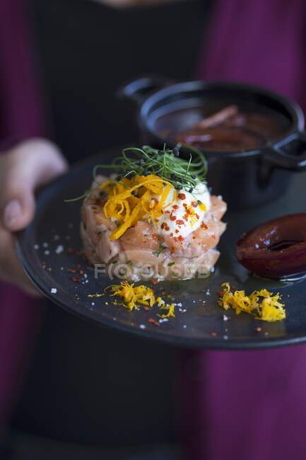 Filete de salmón con chiles machacados, nata fresca, ralladura de naranja, brotes y salsa de ciruela - foto de stock