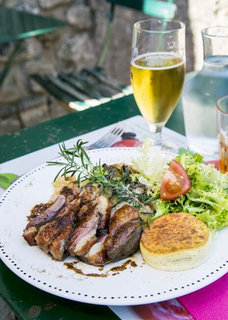 Grilled duck breast with rosemary and salad on restaurant table — Stock Photo