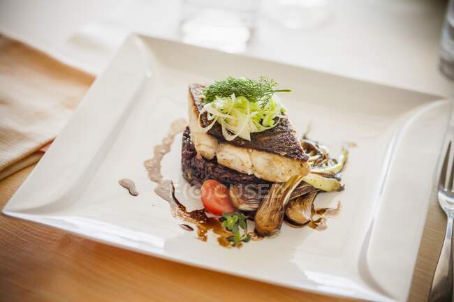 Dorade fillet on black rice with spring onions in a balsamic sauce — Stock Photo