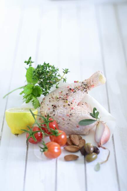 Jambe de poulet épicée avec oignon, olives, amandes, tomates cerises, citron et herbes — Photo de stock