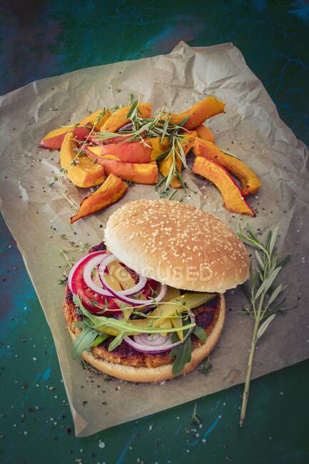 A burger with grilled pumpkin wedges on the side — Stock Photo