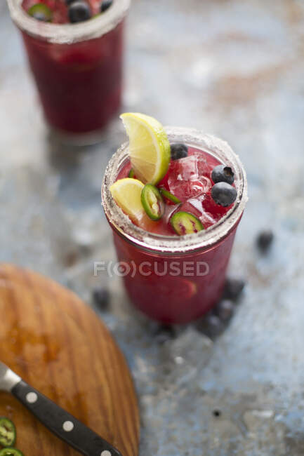 Margarita cocktails in glasses with sugar, blueberries, green chili and lime — Stock Photo