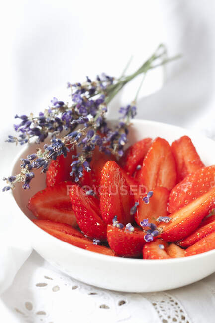 Erdbeeren in Scheiben geschnitten mit Lavendelblüten in Schüssel — Stockfoto