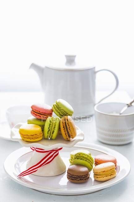 Assorted Colorful Macarons on Cake Stand by tea pot and cup — Stock Photo