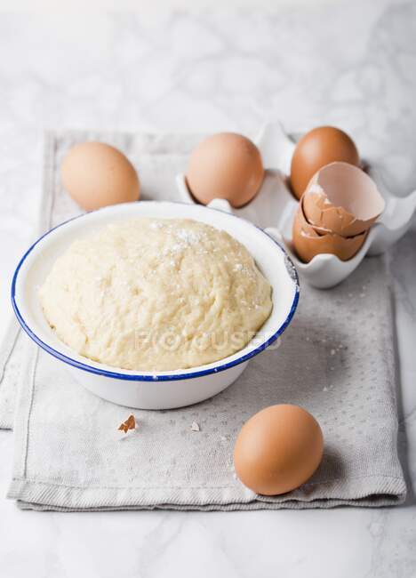 Dough in an enamel bowl and eggs — Stock Photo