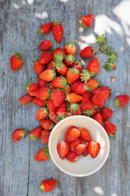 Fresh strawberries on rustic wooden surface and in mini bowl — Stock Photo
