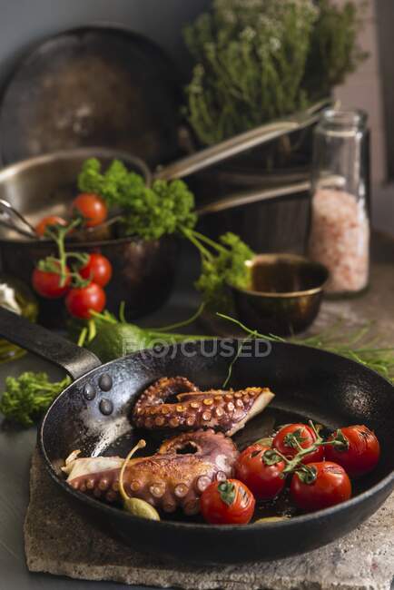 Fried octopus with tomatoes and capers in a pan — Stock Photo