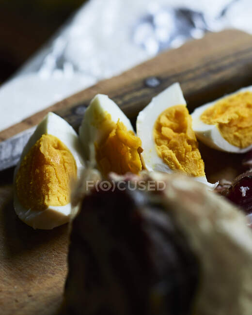 Boiled eggs cut in wedges on wooden board — Stock Photo