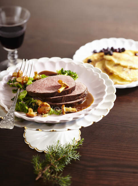 Roasted saddle of venison with savoy cabbage and chanterelle mushrooms and blueberry pancakes — Stock Photo