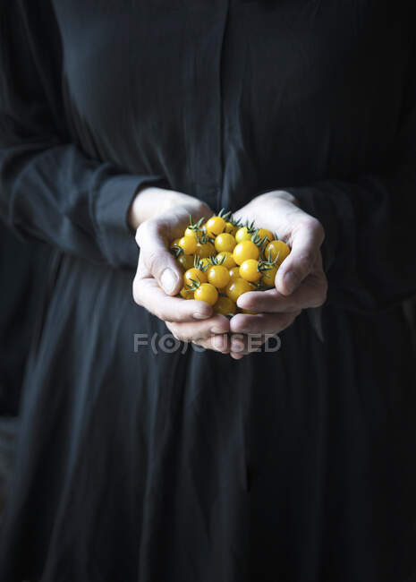 Жінка тримає жовті помідори вишні — стокове фото