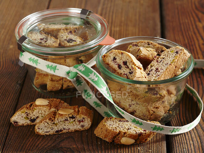 Cantuccini with cranberries in glass jars with ribbon — Stock Photo