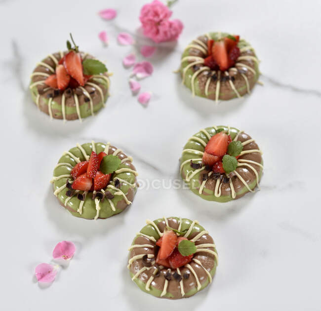 Vegan matcha and chocolate cakes with white chocolate glaze and fresh strawberries — Stock Photo