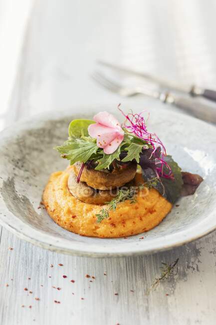 Carrot polenta with mushrooms, served with greens and flower — Stock Photo