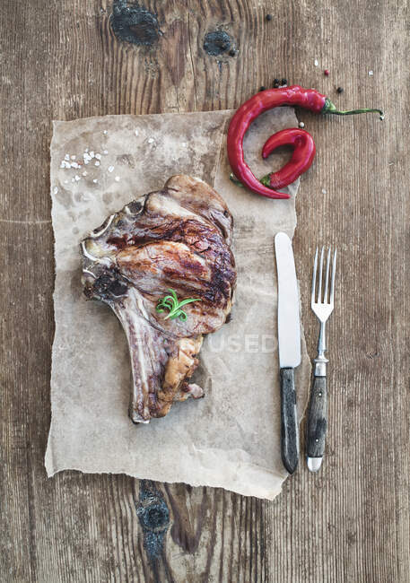 Cooked meat ribeye steak with spices, red chili and rosemary — Fotografia de Stock
