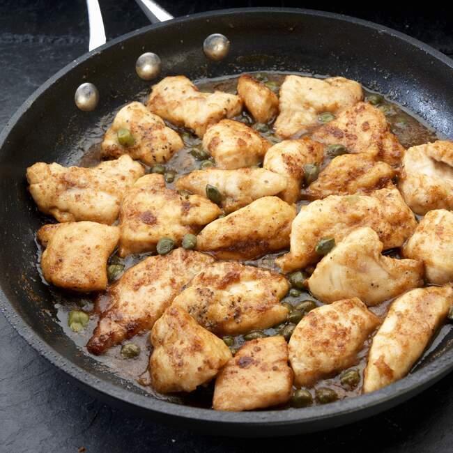 Trozos de pechuga de pollo saludados con aceite de oliva y alcaparras - foto de stock