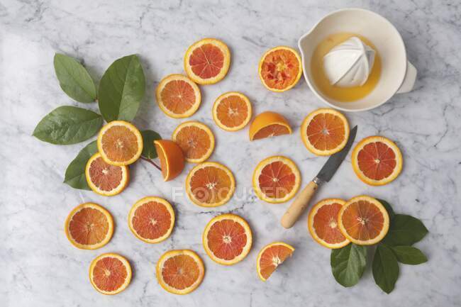 Fatias de laranja com uma prensa cítrica em um fundo de mármore — Fotografia de Stock