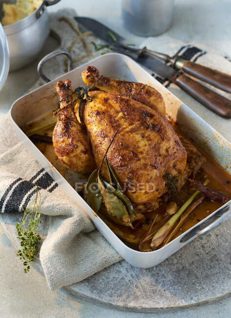 Roast chicken in a roasting tin with linen cloth on stone platter — Stock Photo