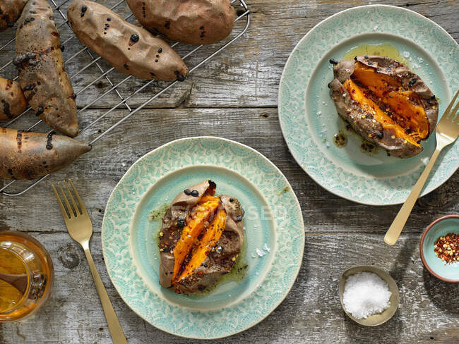 Baked sweet potatoes with spices on plates and rack — Foto stock