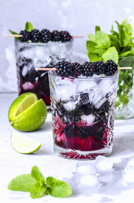 Cocktails à la chaux, à la menthe et aux mûres dans des verres en cristal avec glace et sirop — Photo de stock