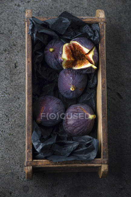 Figos frescos em caixa de madeira com papel preto — Fotografia de Stock