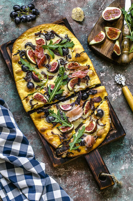 Pizza with mozzarella, figs, black grapes, hamon and arugula — Stock Photo