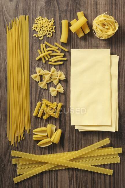 Vari tipi di pasta su una superficie di legno — Foto stock