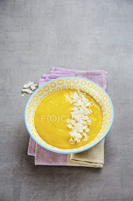 Bol de smoothie à la mangue jaune coloré avec copeaux de noix de coco — Photo de stock