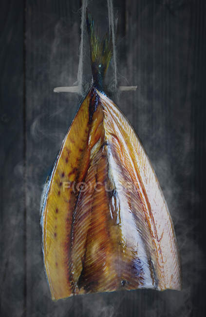 Un pez arenque (arenque ahumado) que se fuma en un fumador - foto de stock
