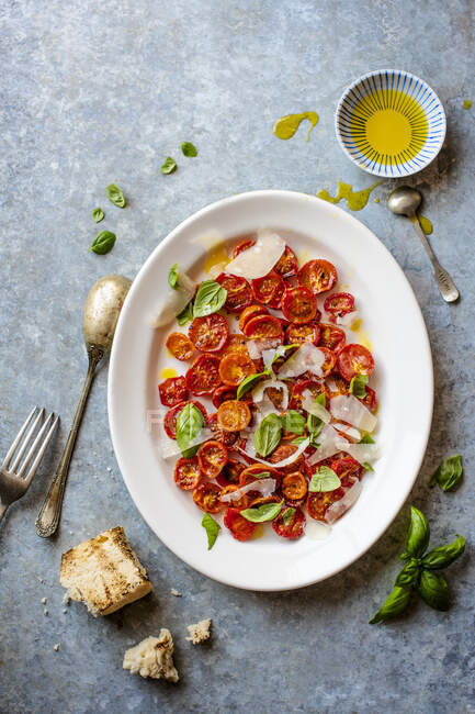 Oven dried tomatoes salad with olive oil, parmesan cheese and basil leaves — Stock Photo