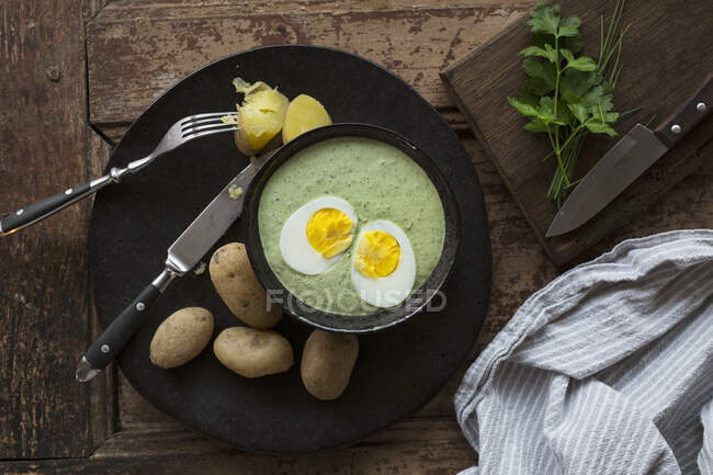Salsa verde con huevo partido y papas nuevas - foto de stock