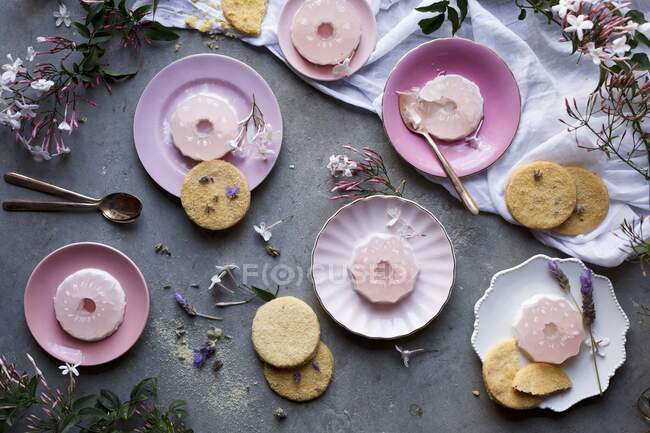 Tavola disordinata con fiori, gelatina rosa e biscotti — Foto stock