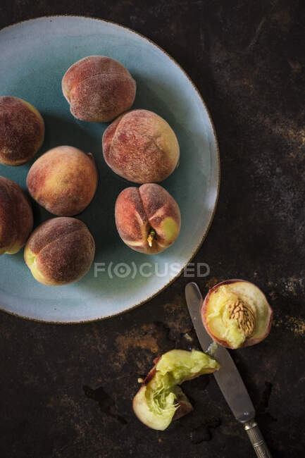 Small Franconian peaches on plate and halved on table with knife — Stock Photo