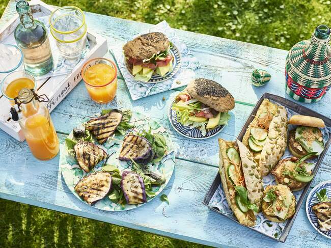 Una tavola apparecchiata in un giardino con panini e bevande — Foto stock
