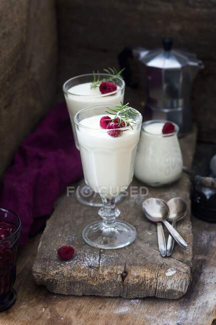 Vanilla panna cotta with with fresh raspberries and rosemary in glasses — Stock Photo