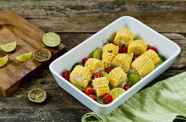 Roasted corn on the cob with cherry tomatoes and limes — Stock Photo