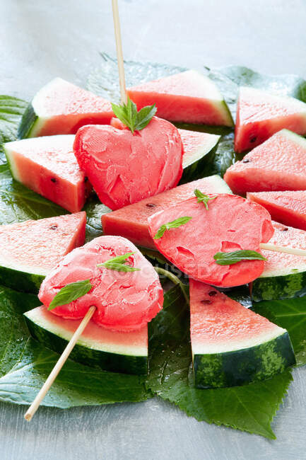 Heart-shaped watermelon popsicles on slices of watermelon — Stock Photo