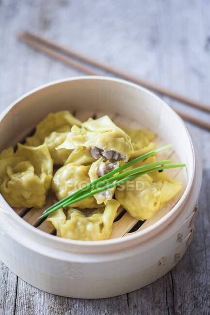 Won tons with chives in a bamboo steamer — Stock Photo