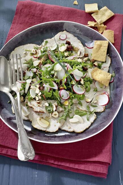 Veal carpaccio with radishes, rocket and hazelnuts — Stock Photo