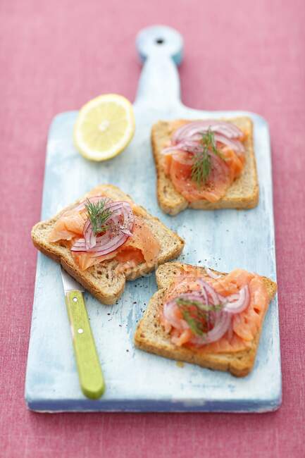 Wholemeal toasts with smoked salmon and red onion — Stock Photo