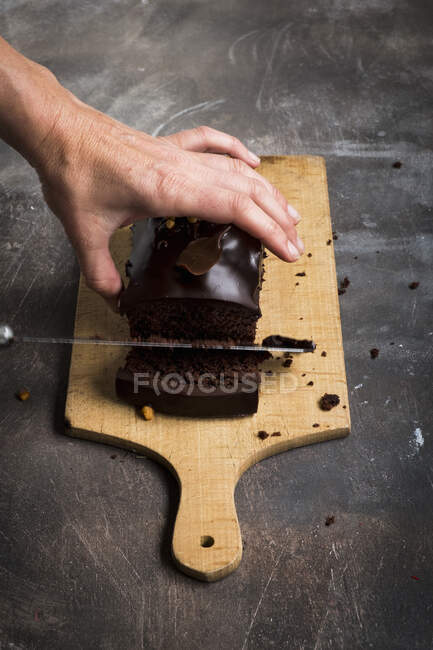 Jemand schneidet Schokoladenkuchen — Stockfoto