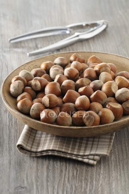 Hazelnuts in a wooden bowl with a nutcracker — Stock Photo