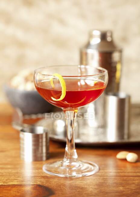 Herb liqueur with lemon zest in cocktail glass — Stock Photo