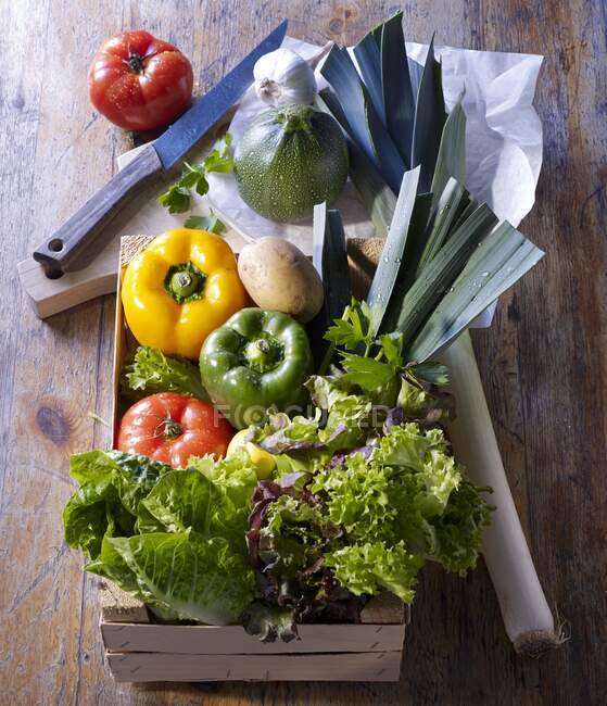 Market vegetables in a wooden box and on a wooden board with paper — Stock Photo