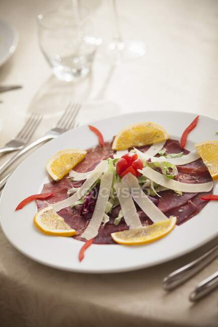 Bresaola with parmesan strips and orange slices — Stock Photo