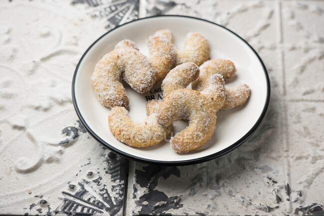 Plate of vanilla crescent biscuits on rustic surface — Stock Photo
