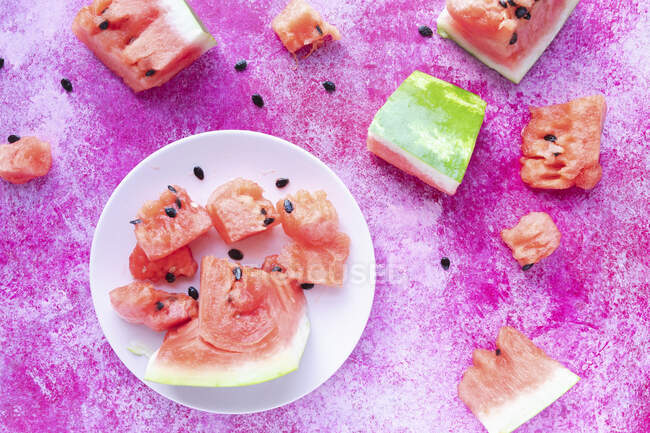 Rodajas de sandía en plato blanco sobre superficie rosa - foto de stock