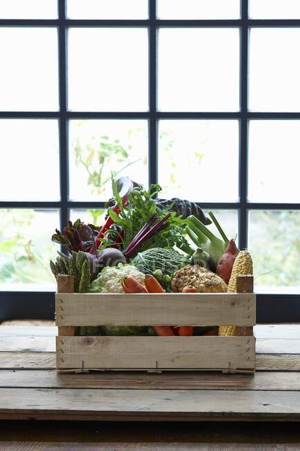 Una caja de verduras frente a una ventana - foto de stock