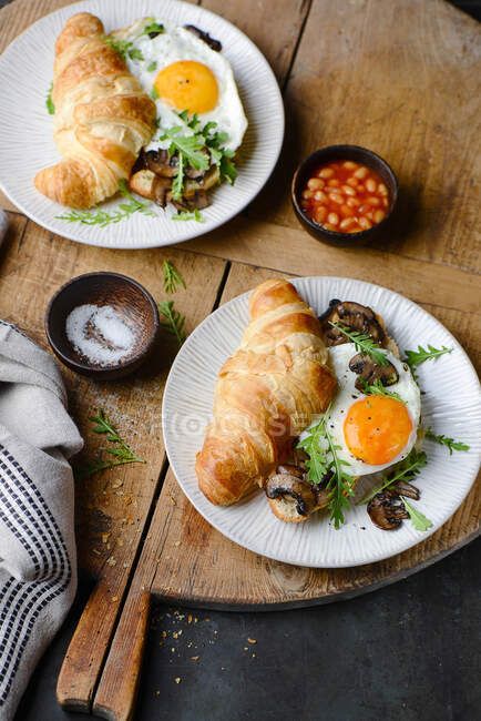 Croissant sandwich with fried eggs and mushrooms — Stock Photo